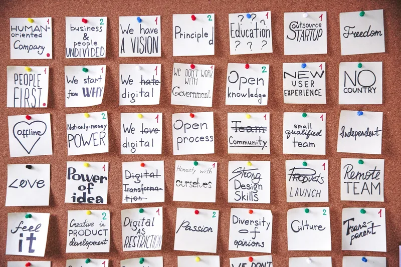 A corkboard with sticky notes and printed customer quotes from pre-launch conversations pinned across it