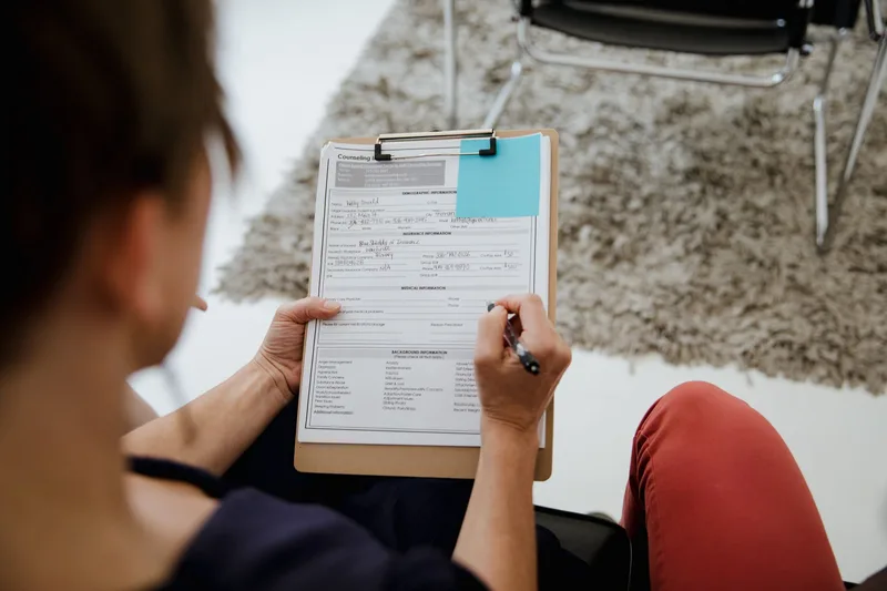 A woman completing a customer research form during a business meeting — the kind of structured feedback that replaces friendly validation