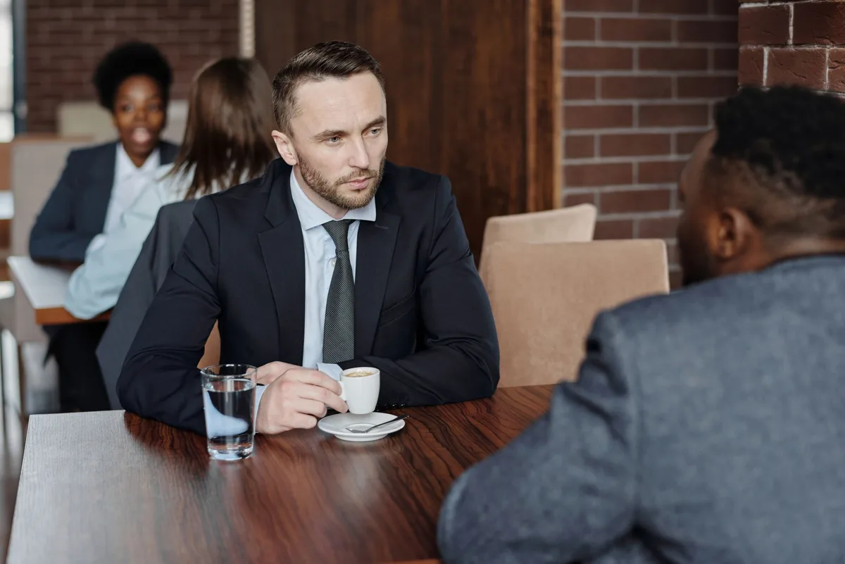Two founders talking over coffee — illustrating how friend feedback on a business idea feels like validation but contains almost no usable market signal