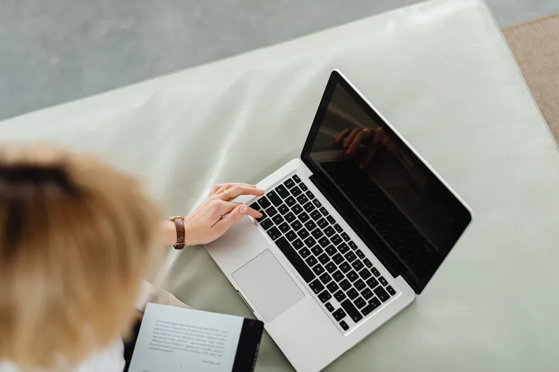 A person researching a business idea’s market demand on a laptop, checking forums and competitor pages for existing demand signals