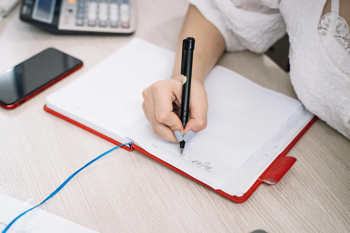 A solopreneur writing notes on a structured validation planning sheet at a desk