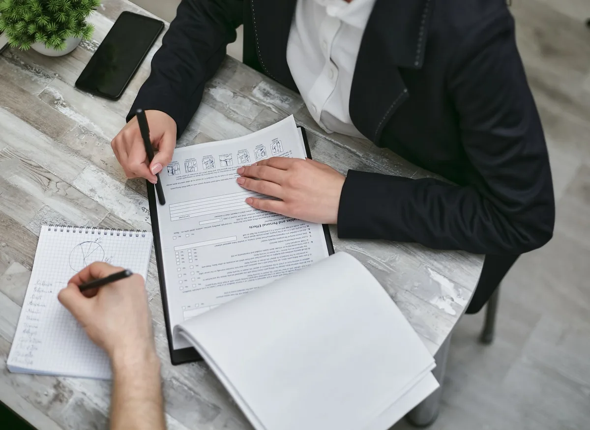 A solopreneur reviewing a structured product market fit checklist at a desk with a notebook and laptop