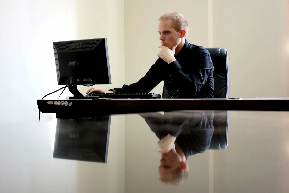 A businessman in deep thought at his desk, reflecting on work tasks — representing the moment a founder evaluates whether to continue