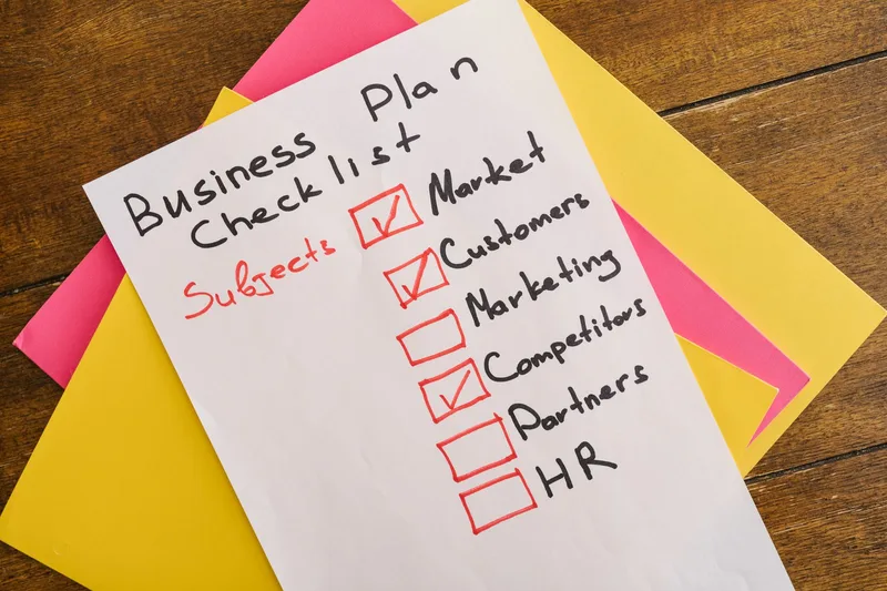 A handwritten business plan checklist on a table — representing the structured idea audit process
