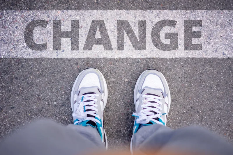 Close-up of sneakers on a street with a &lsquo;Change&rsquo; overlay, representing the walk-away decision and the move toward something new