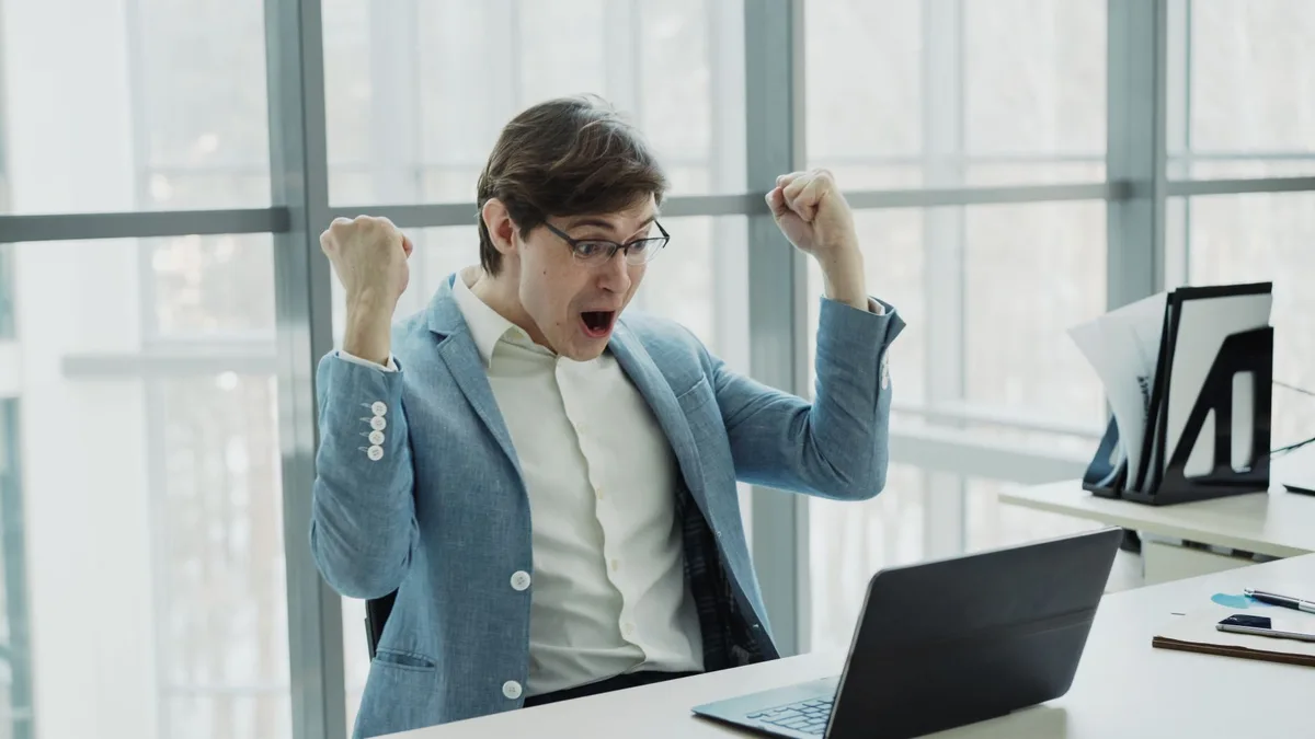 A businessman celebrates success at his desk, excited to launch a new product